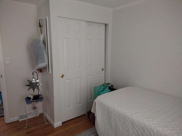 bedroom with baseboards, ornamental molding, and wood finished floors