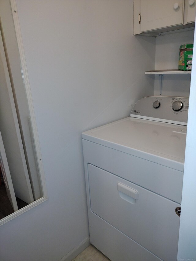 clothes washing area featuring cabinet space, washer / dryer, and baseboards