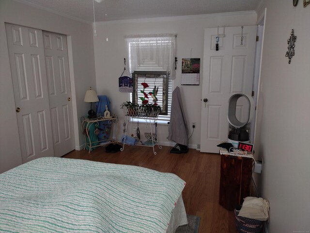 bedroom featuring a closet, crown molding, baseboards, and wood finished floors