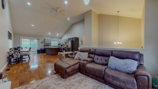 living area with high vaulted ceiling, recessed lighting, ceiling fan with notable chandelier, visible vents, and light wood finished floors