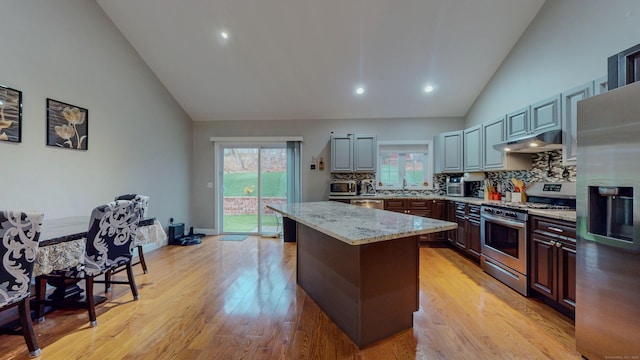 kitchen featuring plenty of natural light, a kitchen island, stainless steel appliances, light wood-type flooring, and under cabinet range hood