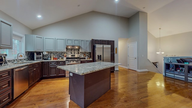 kitchen with a center island, stainless steel appliances, an inviting chandelier, a sink, and under cabinet range hood