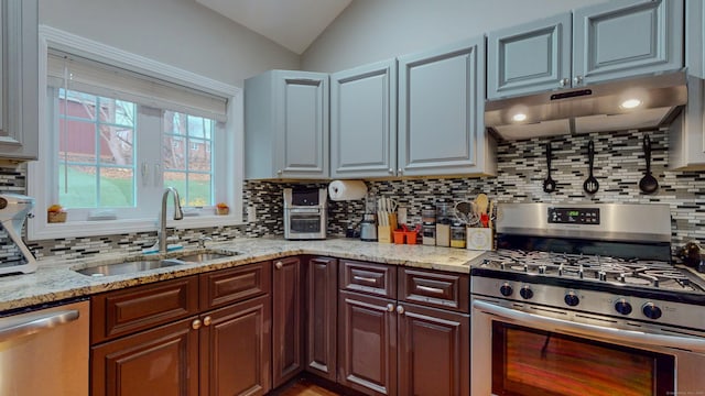 kitchen featuring under cabinet range hood, stainless steel appliances, a sink, vaulted ceiling, and decorative backsplash