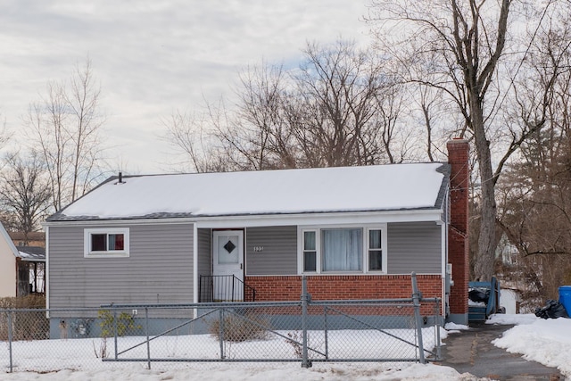 view of front facade with a fenced front yard, brick siding, and a chimney