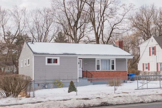 view of front facade with a fenced front yard, a chimney, and brick siding