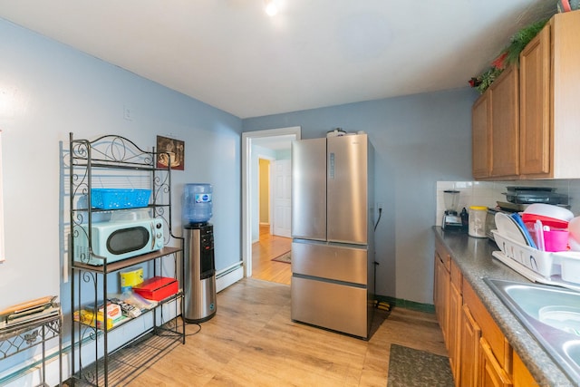 kitchen with light wood-style flooring, brown cabinetry, freestanding refrigerator, and tasteful backsplash