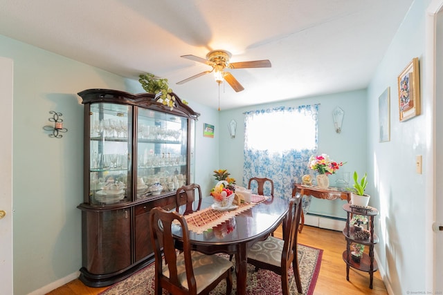 dining room featuring a baseboard heating unit, light wood-type flooring, ceiling fan, and baseboards