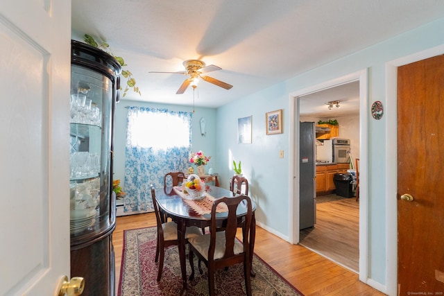 dining space featuring ceiling fan, light wood-style flooring, and baseboards