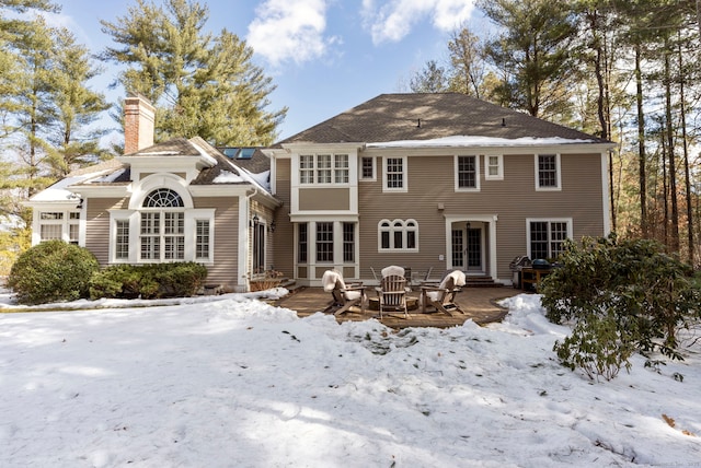 snow covered property featuring entry steps and a chimney