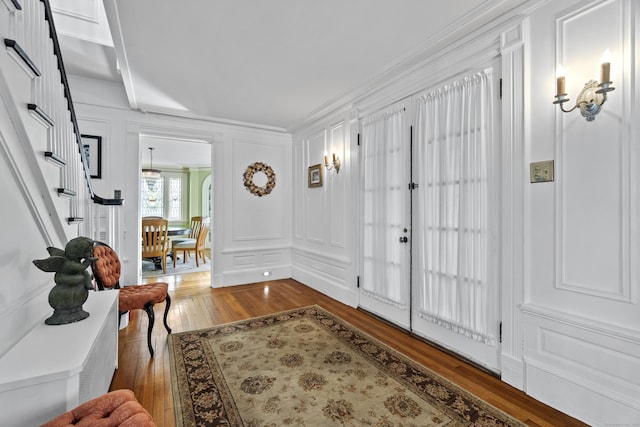 entrance foyer featuring ornamental molding, hardwood / wood-style floors, stairs, and a decorative wall