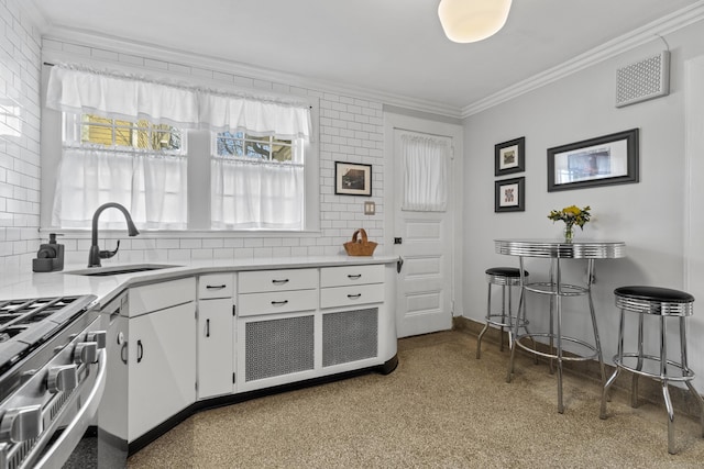 kitchen featuring light countertops, backsplash, ornamental molding, white cabinetry, and a sink