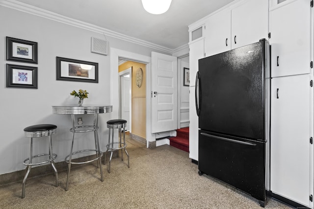 kitchen with baseboards, visible vents, freestanding refrigerator, crown molding, and white cabinetry