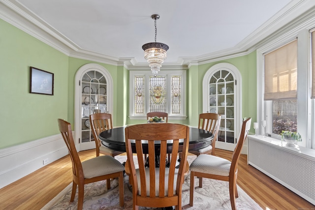 dining space with radiator, light wood-style floors, a wealth of natural light, and a notable chandelier