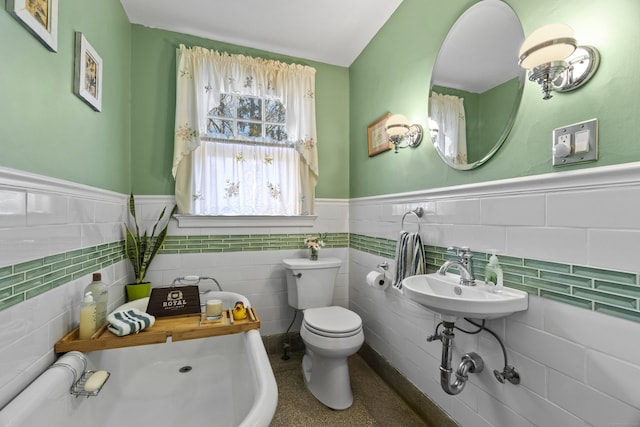 bathroom with toilet, a wainscoted wall, and a sink