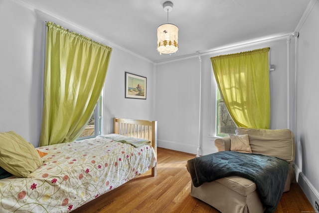 bedroom with crown molding, baseboards, and wood finished floors