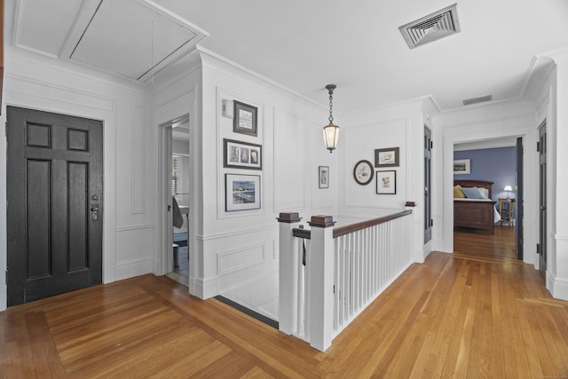 entrance foyer with light wood-style floors, visible vents, and a decorative wall