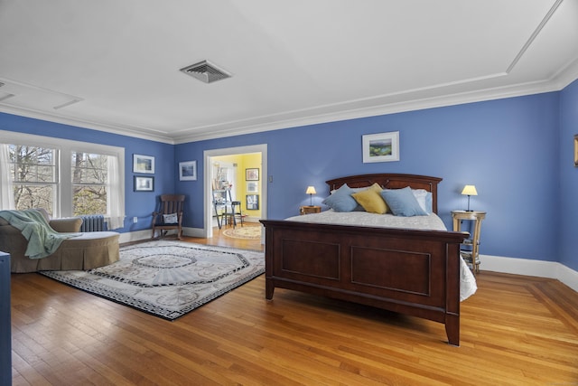 bedroom featuring visible vents, crown molding, light wood-style flooring, and baseboards