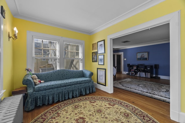 sitting room with baseboards, ornamental molding, and wood finished floors