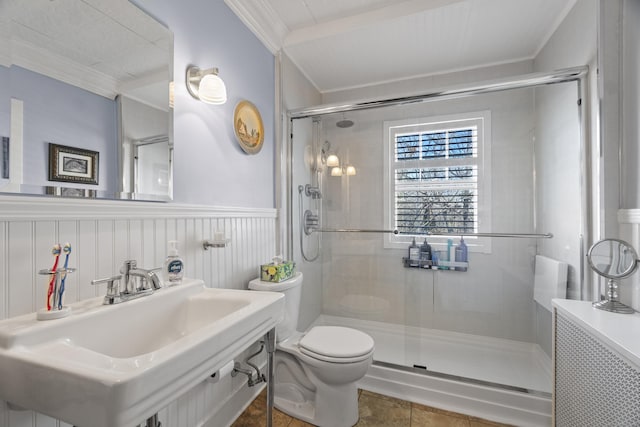 full bath with crown molding, toilet, a stall shower, wainscoting, and a sink