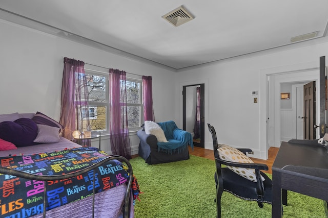 bedroom featuring visible vents, baseboards, and wood finished floors