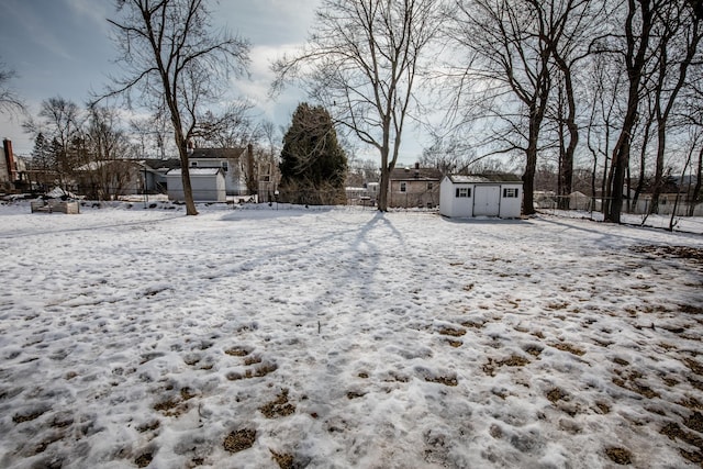 yard layered in snow featuring an outdoor structure, fence, and a shed