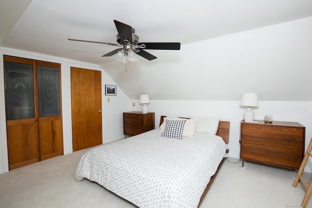 carpeted bedroom with multiple closets, lofted ceiling, and a ceiling fan