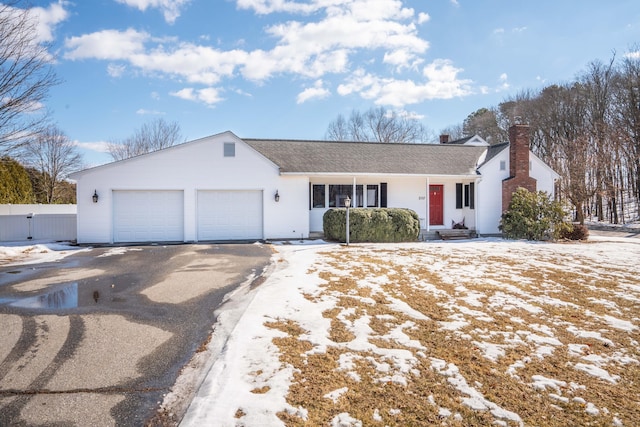 view of front of property featuring driveway, a chimney, roof with shingles, an attached garage, and fence