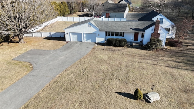 ranch-style house featuring driveway, an attached garage, fence, and a front lawn