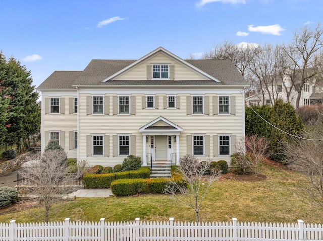 view of front facade with a fenced front yard and a shingled roof