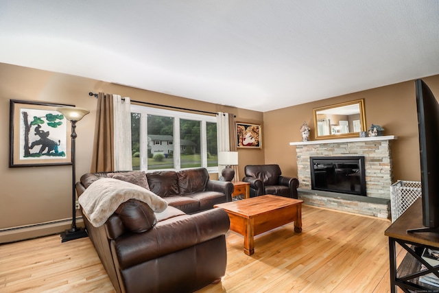 living room with light wood-style flooring, a baseboard heating unit, and a glass covered fireplace