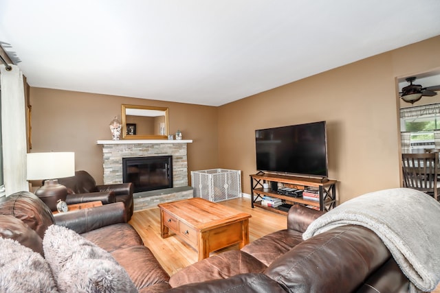 living room with baseboards, wood finished floors, and a stone fireplace