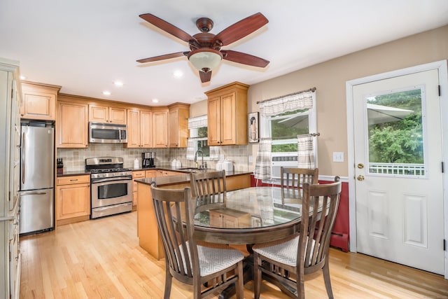 kitchen featuring appliances with stainless steel finishes, dark countertops, a sink, and backsplash