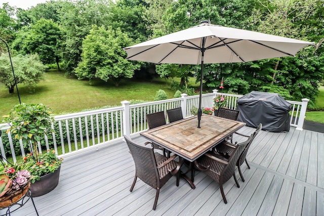 deck featuring outdoor dining space, a lawn, and area for grilling