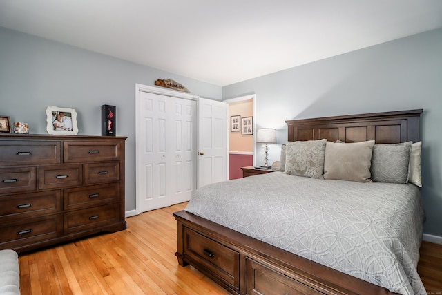 bedroom featuring light wood finished floors, baseboards, and a closet