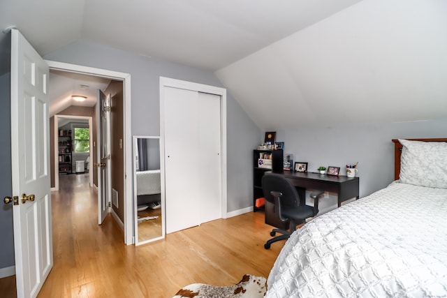 bedroom featuring lofted ceiling, a closet, baseboards, and light wood-style floors