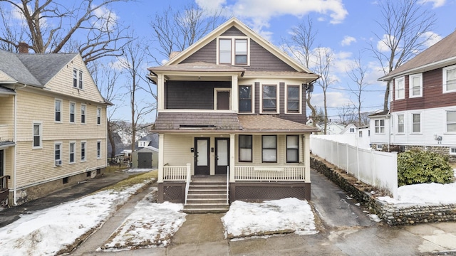 american foursquare style home featuring fence and a porch