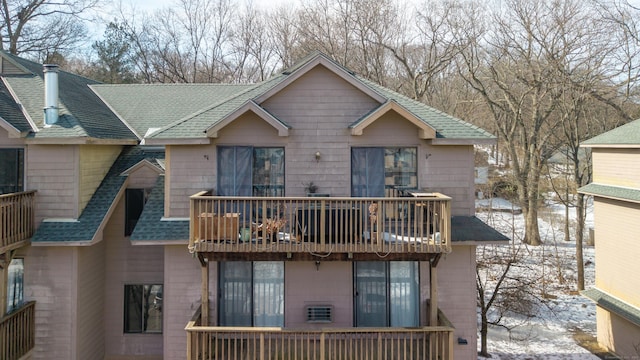 rear view of house with a balcony and a shingled roof