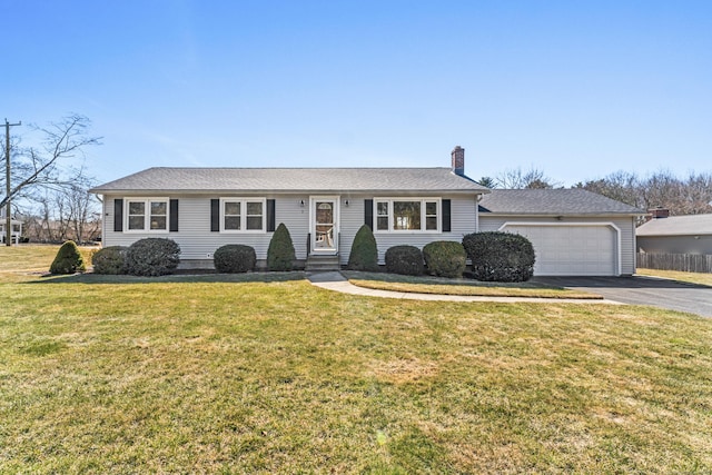 ranch-style home with aphalt driveway, an attached garage, a chimney, and a front lawn