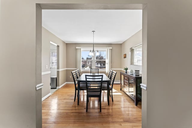 dining space featuring light wood finished floors, baseboards, and an inviting chandelier