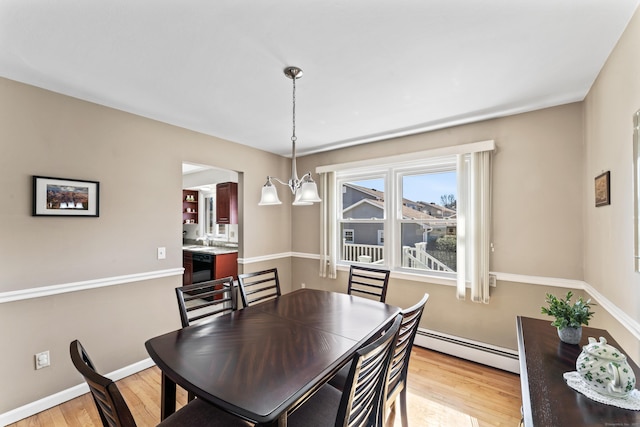 dining area with baseboards, baseboard heating, an inviting chandelier, and light wood-style flooring