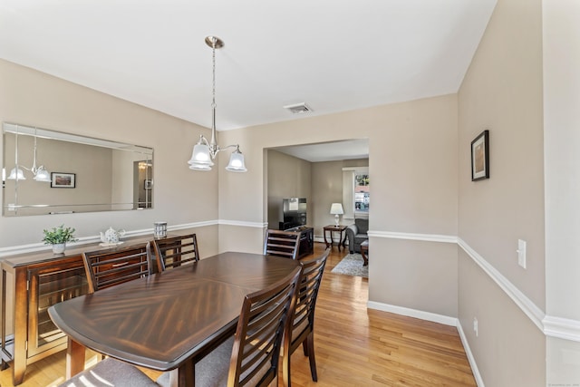 dining room with light wood-type flooring, visible vents, baseboards, and a chandelier