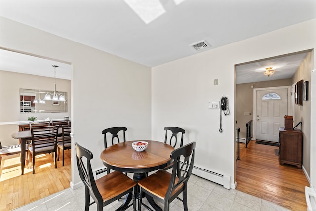 dining space featuring a chandelier, baseboard heating, baseboards, and visible vents