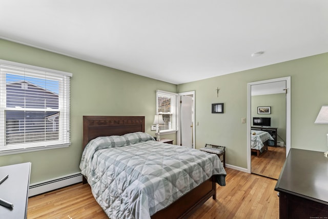 bedroom with light wood-style flooring, baseboards, and baseboard heating