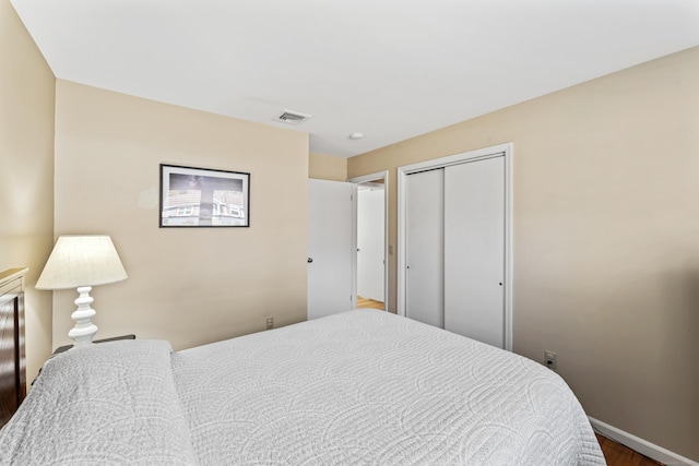 bedroom featuring visible vents, baseboards, a closet, and wood finished floors