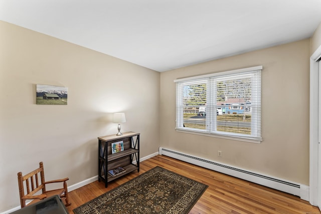 living area featuring wood finished floors, baseboards, and baseboard heating