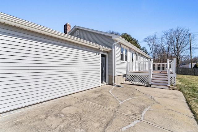 rear view of property with a patio, fence, a chimney, a deck, and a lawn