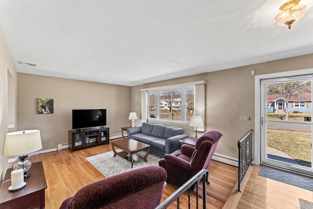 living area with visible vents, baseboard heating, and light wood-style floors