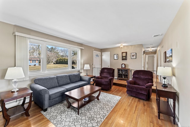 living room with visible vents, a baseboard heating unit, and light wood-style flooring