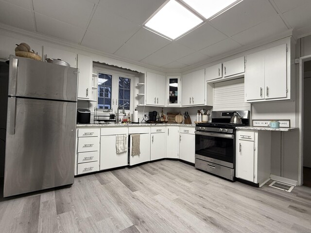 kitchen featuring visible vents, a sink, white cabinets, light wood-style floors, and stainless steel appliances