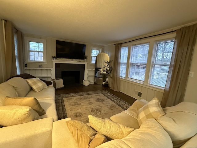 living room featuring a fireplace, visible vents, and wood finished floors